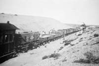 'a_h031 - circa 1930 - Central Australia Railway train waiting for sand to be loaded. The wagons are tank NTSA 604  and NGS open wagons'