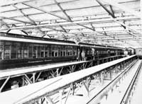 'b05-58b - circa 1917 - Interior of Port Augusta car barn with Trans-Australian being cleaned. BRP18 in foreground (Commonwealth Railways)'